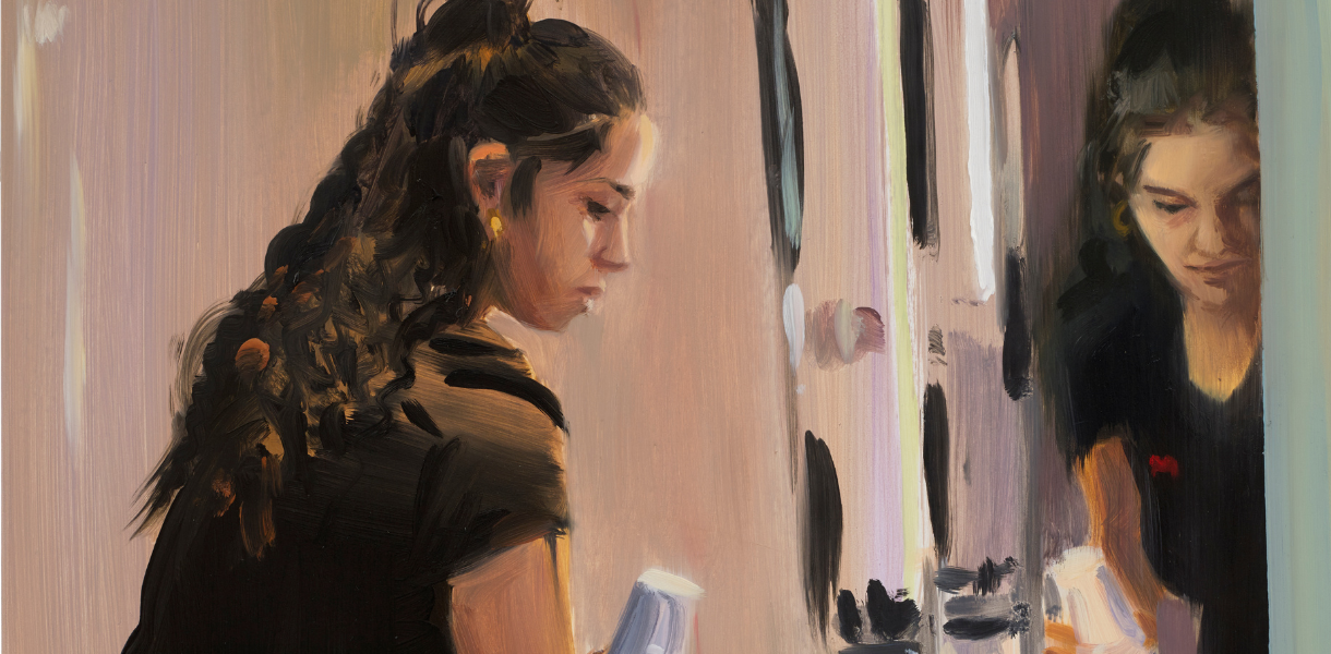 A woman with long, dark hair tied back, wearing a black top, looks down at bathroom objects in front of a mirror. Her thoughtful reflection is visible.